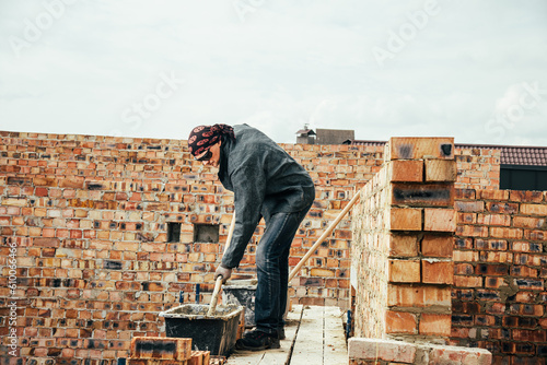 An experienced worker works on the construction of a brick house