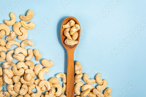 Cashew nuts in a wooden spoon on a blue background