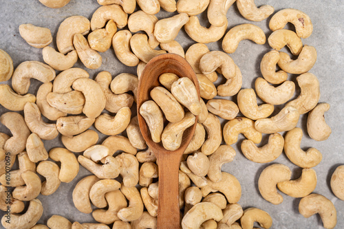 Cashew nuts in a wooden spoon on a gray marble stone background