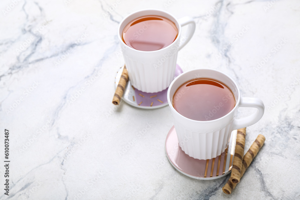 Drink coasters with cups of tea and wafer rolls on white marble table Drink coasters with cups of tea and wafer rolls on white marble table