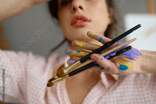 Art portrait of creative female artist showing hand with paintbrush
