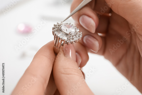 Female jeweler making ring on white table, closeup photo