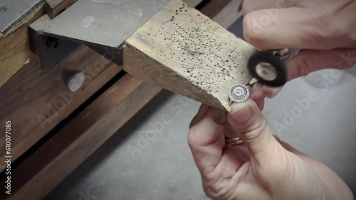 Close-up of jewelers hands polishing ring on a bench pin with polishing wheel