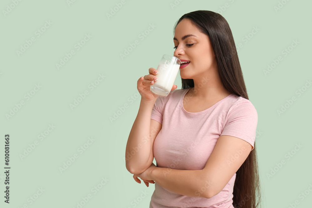Beautiful young woman drinking milk on mint background Beautiful young woman drinking milk on mint background