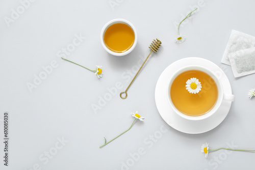 Cup of hot tea with honey and flowers on white background