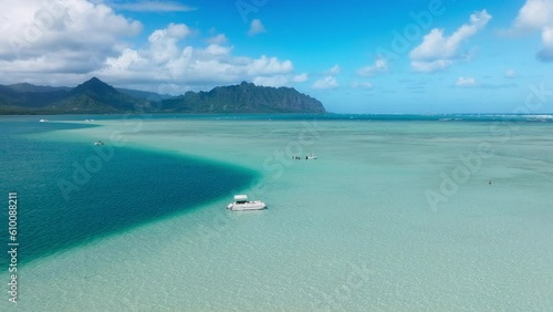 Scenic Oahu shore on Hawaiian paradise island. Amazing nature landscape blue lagoon. Aerial view of boat with snorkelers out on the Kaneohe sandbar tour with cinematic Kualoa Mountains on background