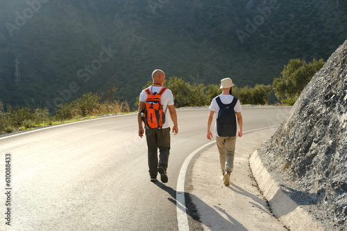 two men with backpacks, mature man 60 years and man 30 years old, backpacker in panama walking along road with magnificent natural scenery, watching nature, concept together travel, summer vacation