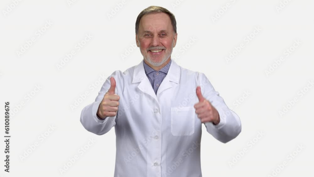 Happy male senior medic in white coat shows both thumbs up. Isolated on white. Happy male senior medic in white coat shows both thumbs up. Isolated on white.