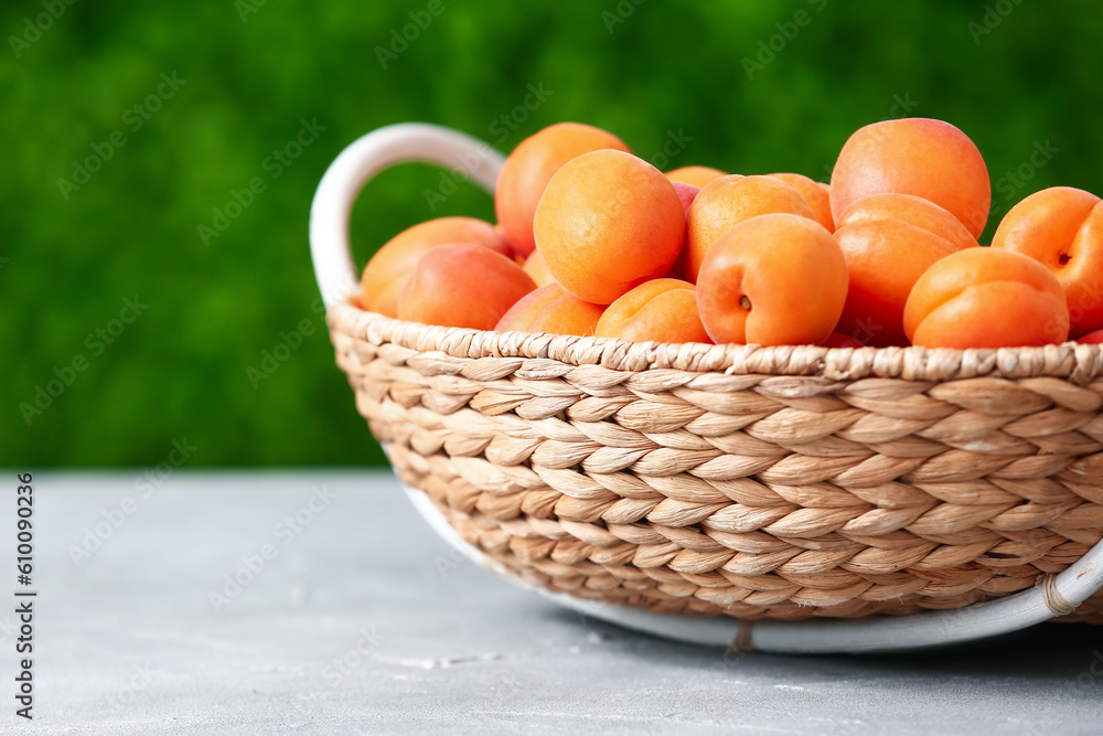 Wicker basket with fresh apricots on table outdoors