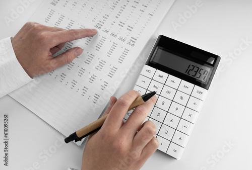 Accountant using a calculator and points her finger at the numbers in the financial statement.
