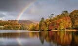  a rainbow is seen over a lake with trees in the foreground and mountains in the background, with a rainbow in the sky above the water.  generative ai