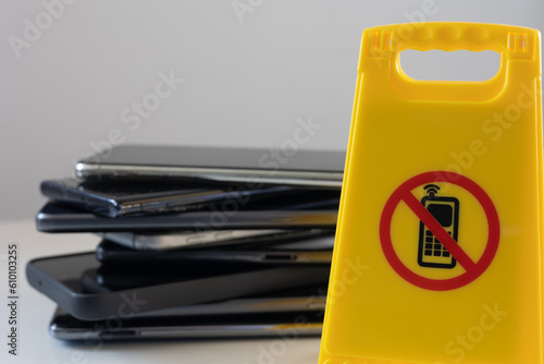Sign prohibiting the use of mobile telephones with telephones on the back on neutral background