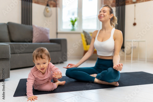 Athletic woman in top and leggins practicing yoga with her baby.