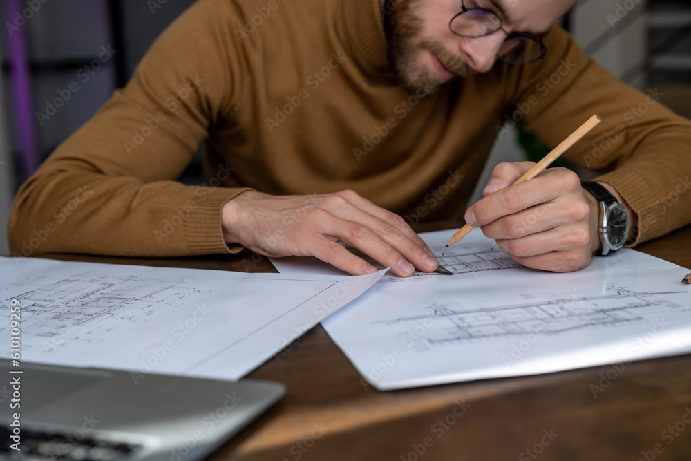 Engineer architect in glasses sitting at the table and creating blueprint thinking about new project Engineer architect in glasses sitting at the table and creating blueprint thinking about new project