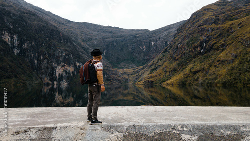 turista con una mochila parada junto al lago en las montañas viendo al horizonte,turista,laguna,paisaje,explorar,concepto de turimo,