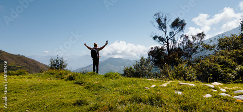Hermosas montañas y hombre joven de pie con mochila en el camino en verano. Paisaje con turista en la cima de la montaña, bosque, colinas, cielo blancos con nubes, Viaje,	