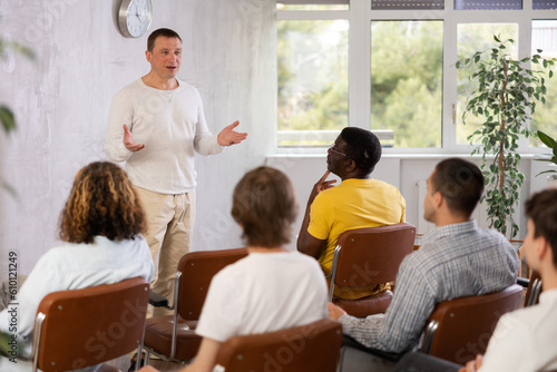 Middle-aged man lecturer conducting lesson for group of interested guys sitting in auditorium