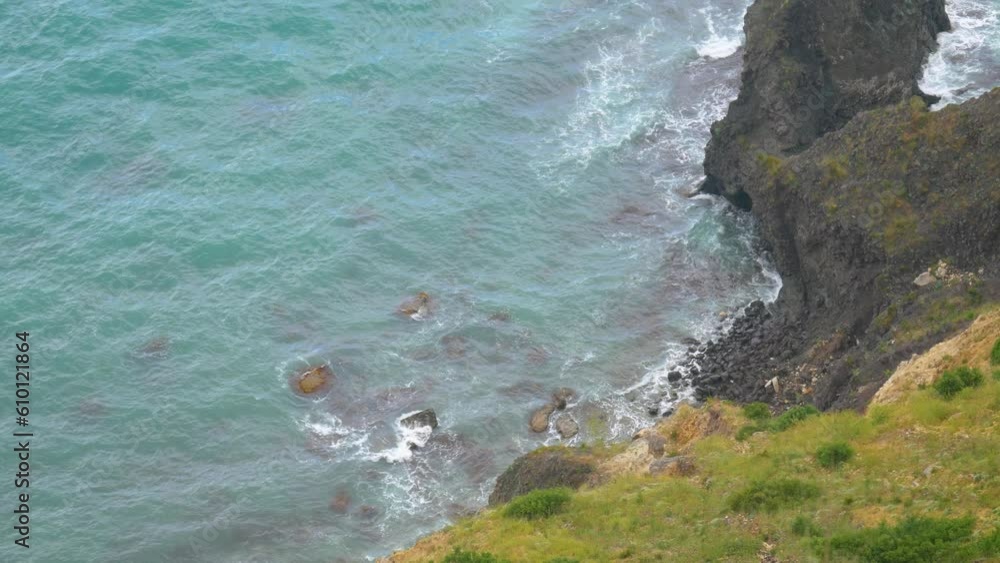 Tidal waves crash against the rocks, viewed from above. Rocky shore and bright azure sea. Tidal waves crash against the rocks, viewed from above. Rocky shore and bright azure sea.