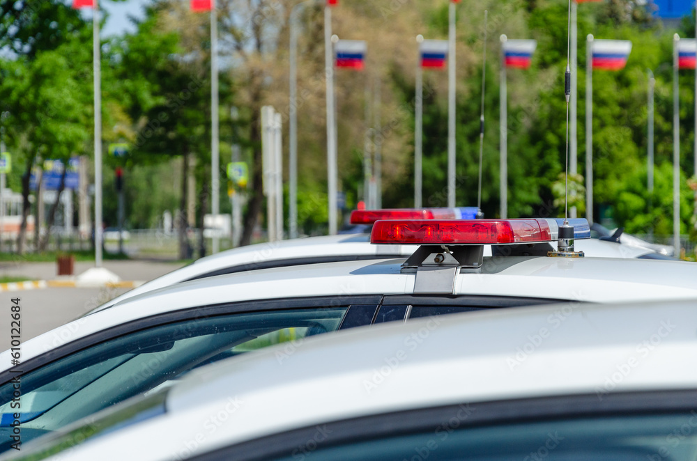 Police car flashing light. In the background, the flags of Russia are out of focus.