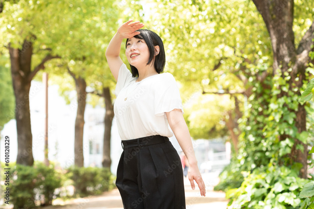 夏の美容イメージに　日差しを眩しがる女性
Portrait of young beautiful asian woman traveler hands protect face from sun light in fresh summer time. 