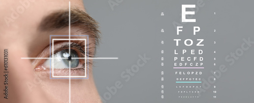 Vision test chart and laser reticle focused on man's eye against light grey background, closeup. Banner design photo