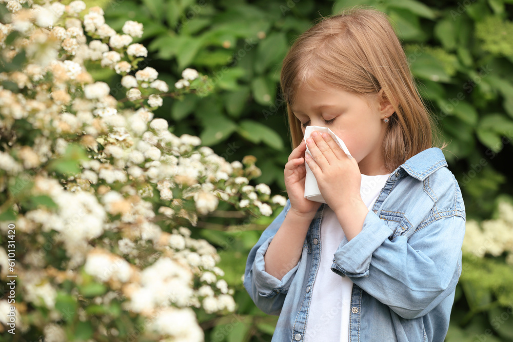 Little girl suffering from seasonal pollen allergy near blossoming tree on spring day Little girl suffering from seasonal pollen allergy near blossoming tree on spring day