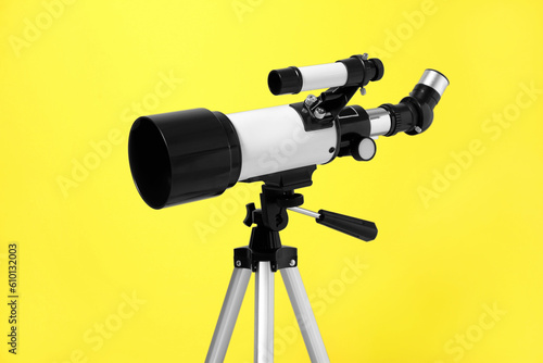 Tripod with modern telescope on yellow background, closeup