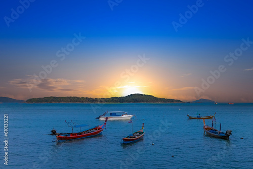Sunset over Rawai Beach in Phuket island Thailand. Lovely turquoise blue waters  lush green mountains colourful skies and beautiful views the pier and long tail boats. Sky is taken seperate from Body 