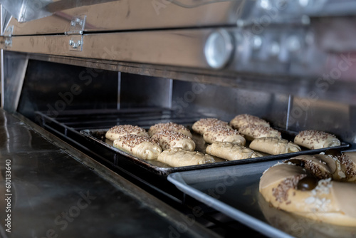 A tray full of pastry cream filled buns with nut toppings are being baked inside the oven