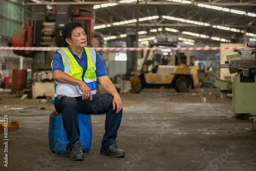 Senior male Industrial factory workers are exhausted and stressed from hard work. Senior man Feeling tired from work. Unhappy, discouraged, hopeless.