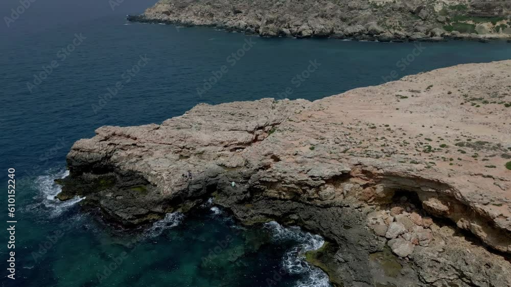 Aerial drone rotating shot over rocky cliffs along shoreline in Marsaskala, Malta at daytime. Aerial drone rotating shot over rocky cliffs along shoreline in Marsaskala, Malta at daytime.
