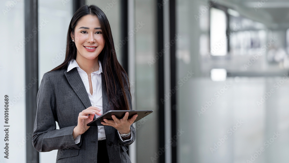 Young Asian businesswoman looking at camera holding tablet at office. Young Asian businesswoman looking at camera holding tablet at office.