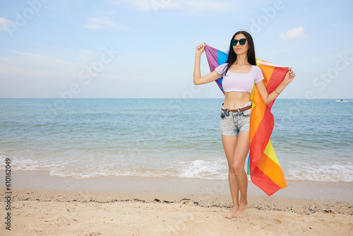 young woman holding a rainbow flag(LGBT) on the beach