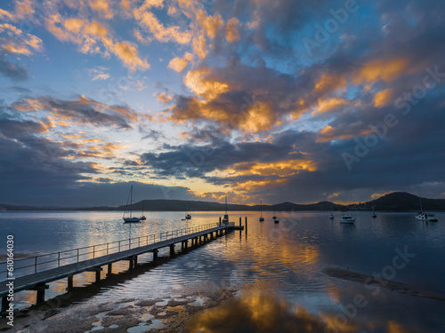 Aerial sunrise over the water with low cloud cover, boats and reflections