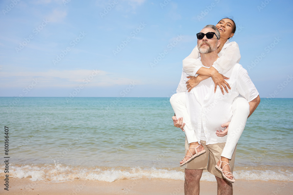 elderly man carrying his girlfriend on the beach and enjoy honeymoon in summer elderly man carrying his girlfriend on the beach and enjoy honeymoon in summer
