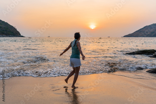 Happy young Asian woman enjoy the moment of sunrise or sunset at the beach. Summer, vacation and holiday concept. Copy space