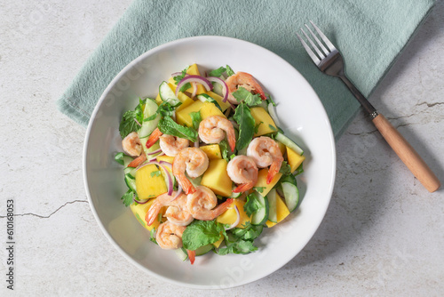 Healthy food shrimp salad has mango cucumber peppermint in bowl on slate background.