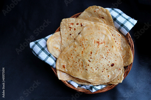Triangle shape Plain Parotha or namak Parantha or tel paratha is an Indian flatbread made of whole-wheat flour, salt, and oil. served in a wooden basket. copy space. photo