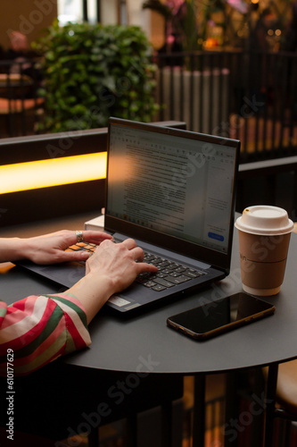 Female hands on keyboard, woman working on a laptop at the table in cafe