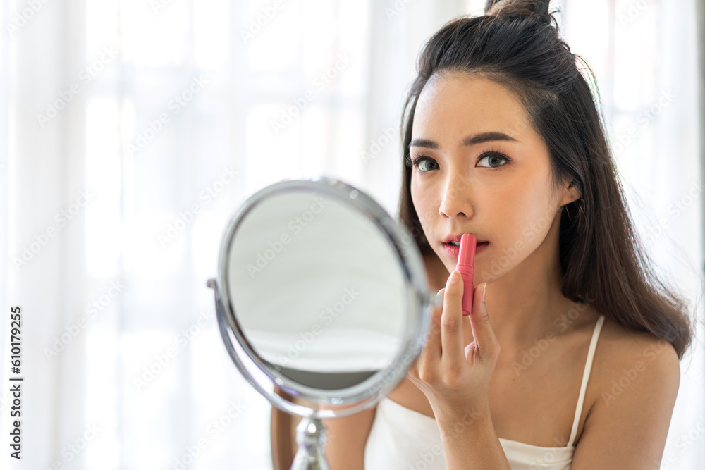Smiling beautiful asian woman fresh healthy skin looking at camara and enjoying applying skincare lips with red lipstick at home.facial beauty and cosmetic concept Smiling beautiful asian woman fresh healthy skin looking at camara and enjoying applying skincare lips with red lipstick at home.facial beauty and cosmetic concept