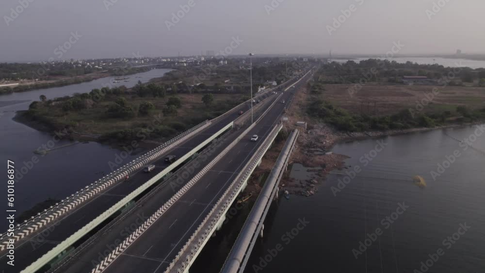 Witness a breathtaking sunset casting its golden hues over a bustling bridge, where traffic weaves its way amidst the tranquil waters below Witness a breathtaking sunset casting its golden hues over a bustling bridge, where traffic weaves its way amidst the tranquil waters below