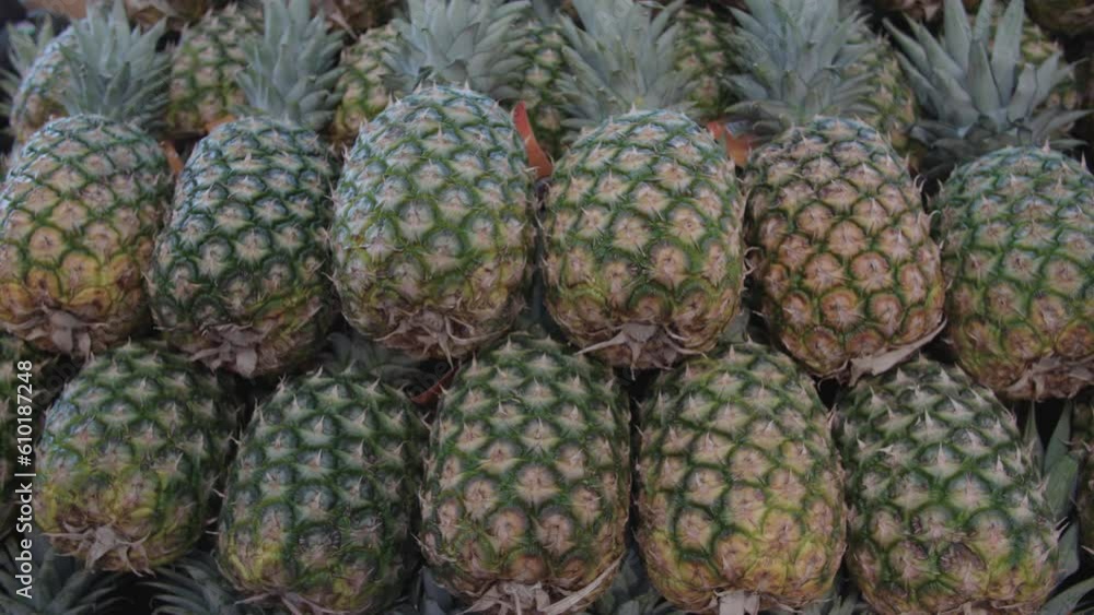 Stacks of raw pineapples on their sides in the produce section at the grocery market. Stacks of raw pineapples on their sides in the produce section at the grocery market.