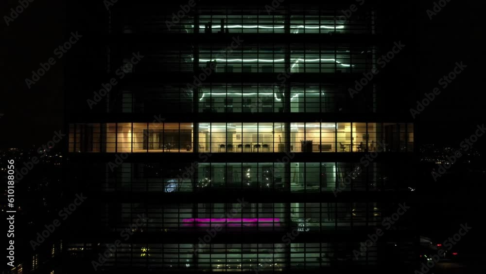 Drone shot outside the windows of an office building at night. Close-up of windows of offices in a skyscraper, business center of Copenhagen. Drone shot outside the windows of an office building at night. Close-up of windows of offices in a skyscraper, business center of Copenhagen.