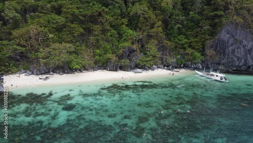 Tourists People snorkeling, swimming and sunbathing at Paradise Beach on Cadlao Island, El Nido. Aerial photo