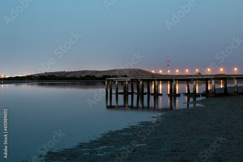 Beautiful after-sunset shot of a lake with a wooden footbridge, captured from a mangrove beach in Umm Al Quwain, United Arab Emirates. photo