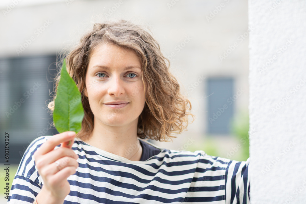 young woman with green leave in the hand in the city
