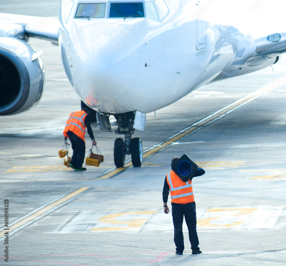 Workers helping to stop and direct plane at airport Workers helping to stop and direct plane at airport