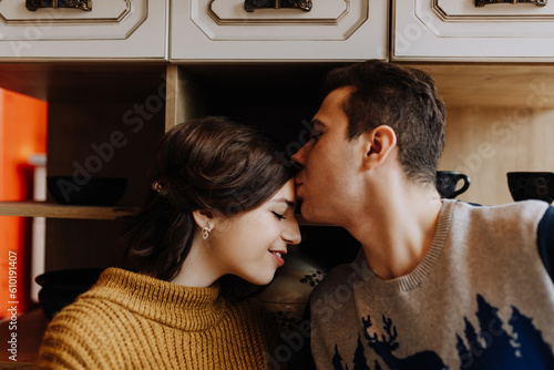 couple is hugging while sitting in kitchen in middle of Christmas photo