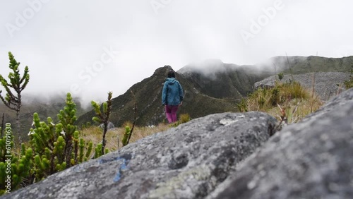 Woman walking through paramo mountain path in a cloudy day photo