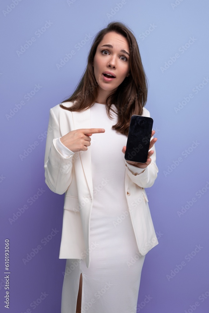 a woman with dark long hair in an elegant white dress demonstrates the screen of a smartphone with a mockup a woman with dark long hair in an elegant white dress demonstrates the screen of a smartphone with a mockup